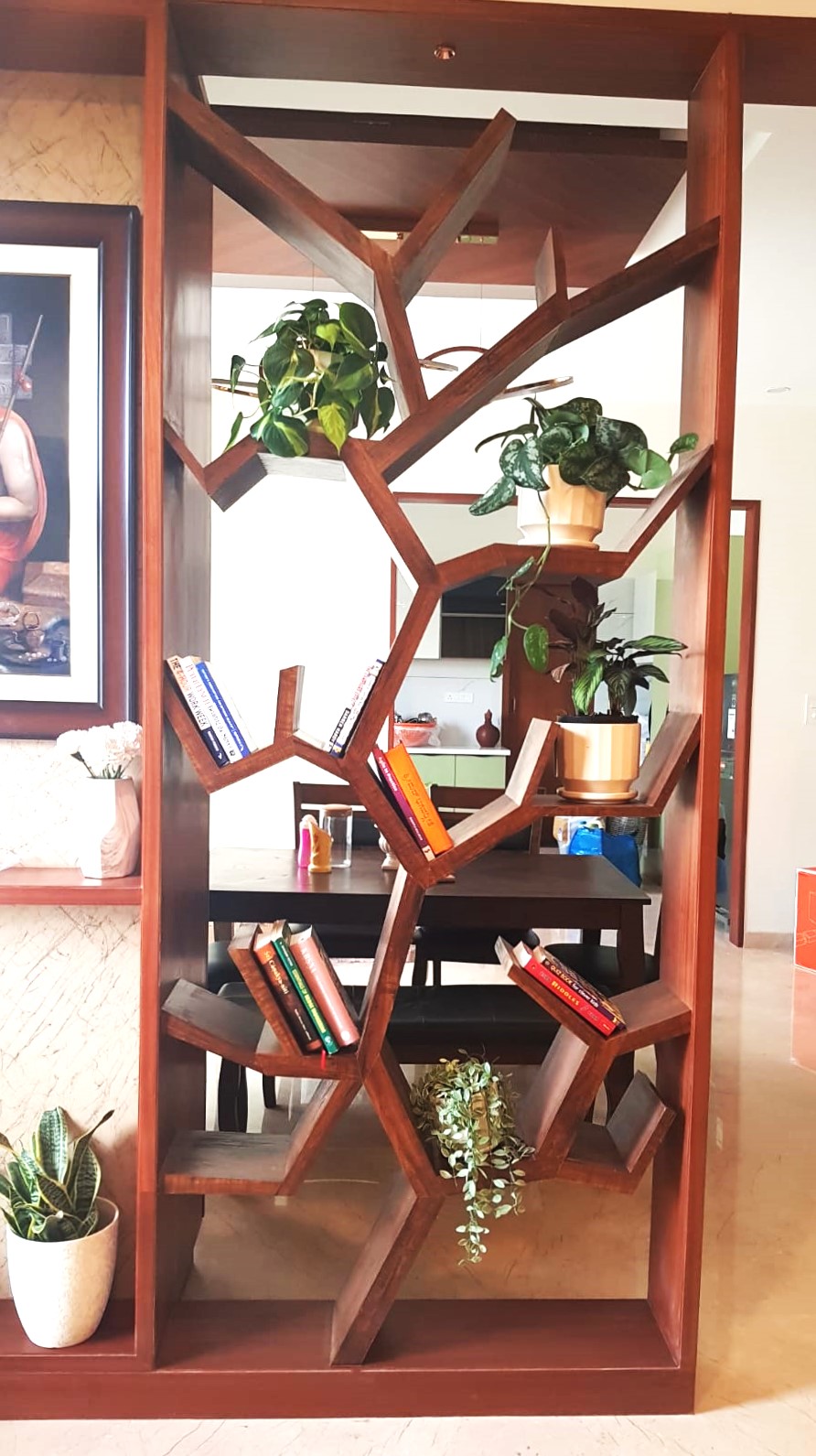 Branching timber shelving unit built as a room divider in a Bengaluru apartment