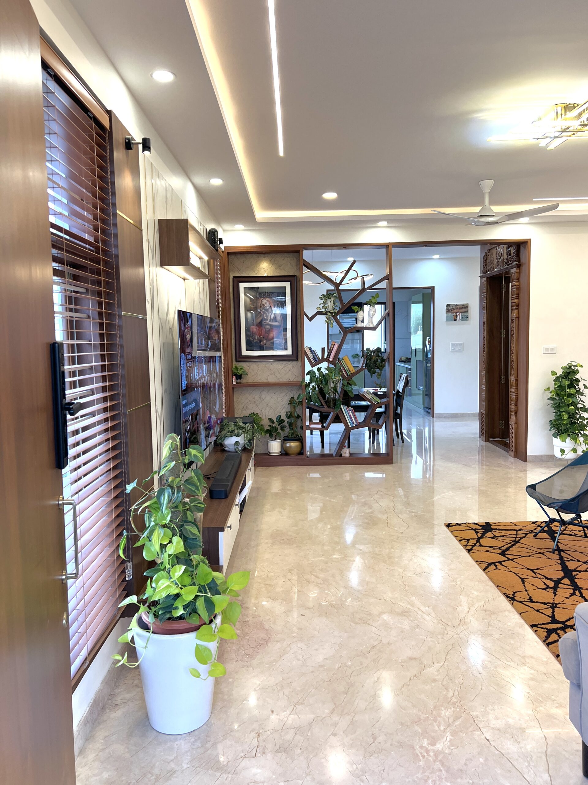 Open-plan living and dining area with a timber screen, marble flooring and fitted media wall